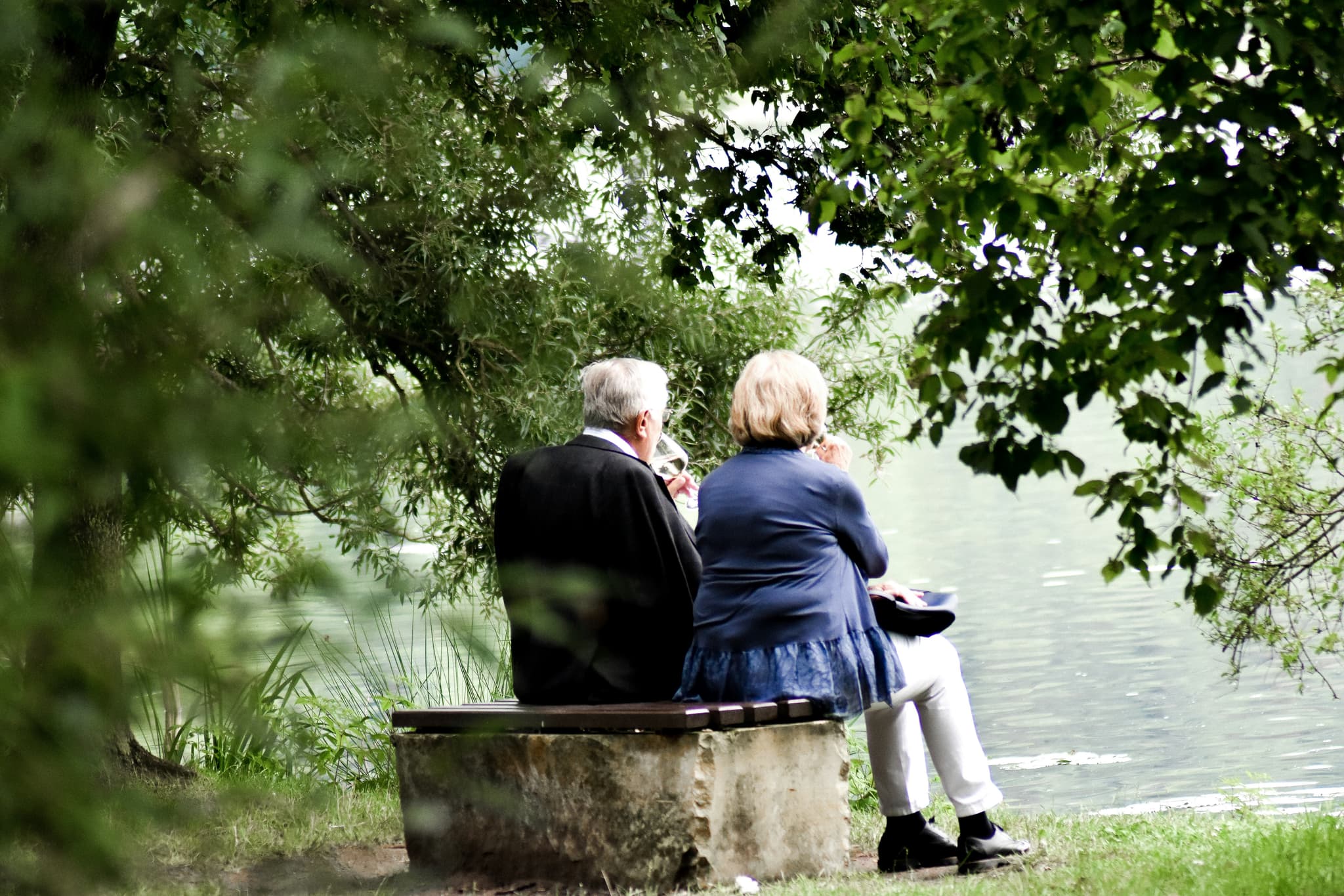 Elderly resting on a bench by a river